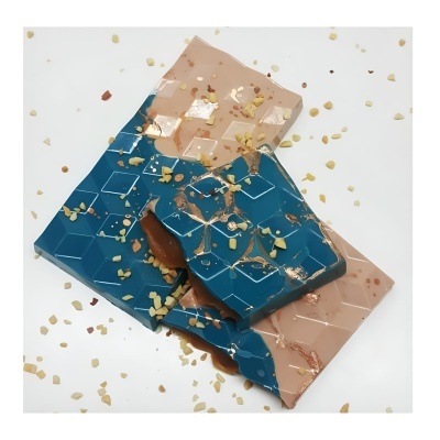 Barra de chocolate azul e bege com textura de hexágonos e frutos secos