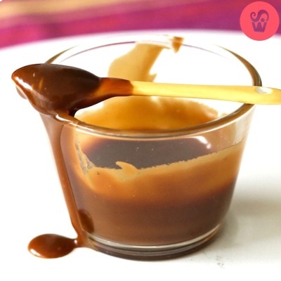 Copo de vidro com creme castanho e colher de cabo amarelo