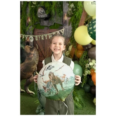 Criança com balão de dinossauros em festa temática Jurassic World