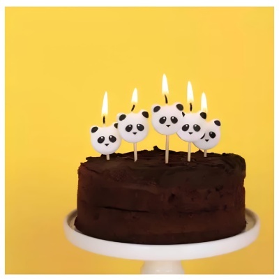Bolo de chocolate com velas acesas em forma de cabeças de panda