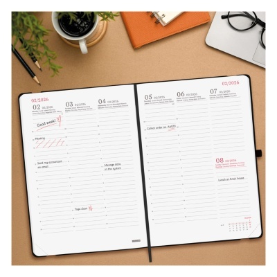 Agenda semanal aberta em formato de página dupla com anotações, sobre superfície com objetos de escritório.