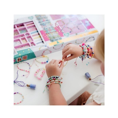 Criança a fazer pulseiras com contas coloridas e material artesanal numa mesa branca.