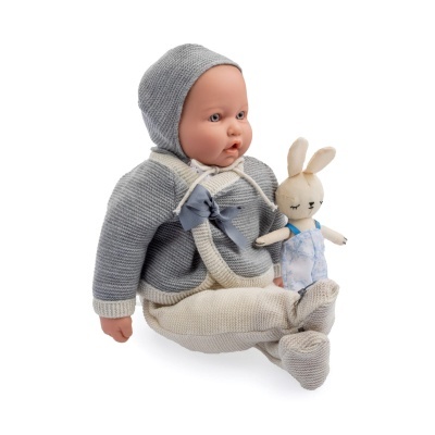 Boneca bebé vestida com roupa de malha cinzenta e creme, segurando coelho de pano branco com fato azul