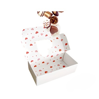 Caixa branca aberta decorada com corações vermelhos e rosa e bombons de chocolate
