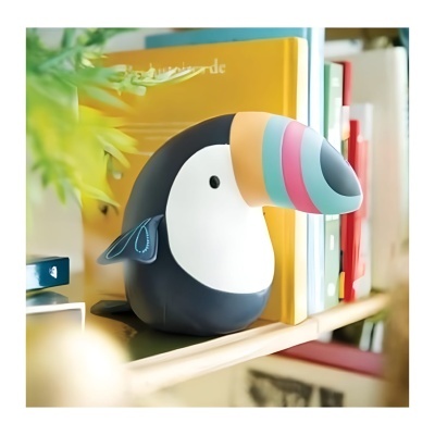 Escultura decorativa de tucano colorido numa estante de madeira com livros e plantas