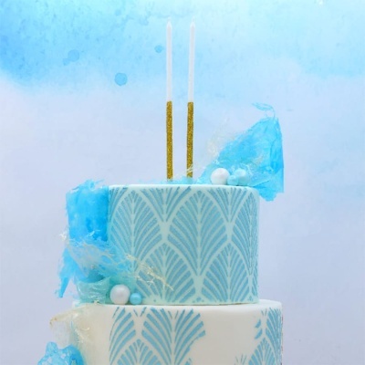 Bolo decorado em azul e branco com velas douradas