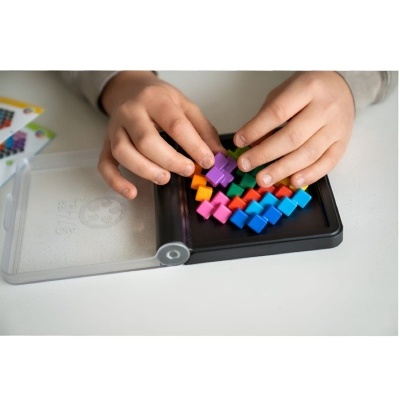 Mãos de criança a jogar com peças coloridas de um jogo de tabuleiro