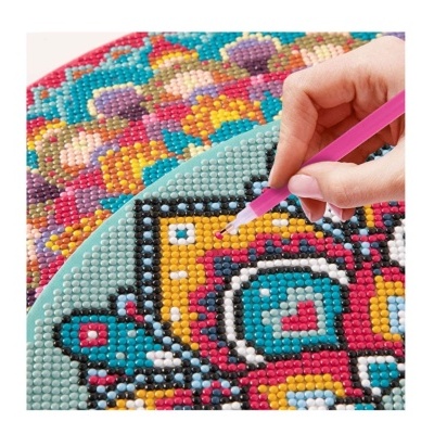 Mão segurando caneta rosa aplicando diamantes em pintura de diamante colorida