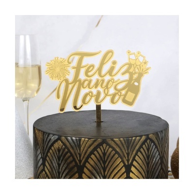 Topo de bolo dourado com mensagem 'Feliz ano Novo' sobre base preta com padrão dourado