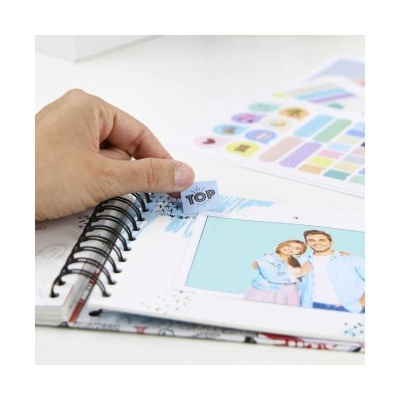 Caderno de argolas aberto com foto de casal e autocolantes coloridos