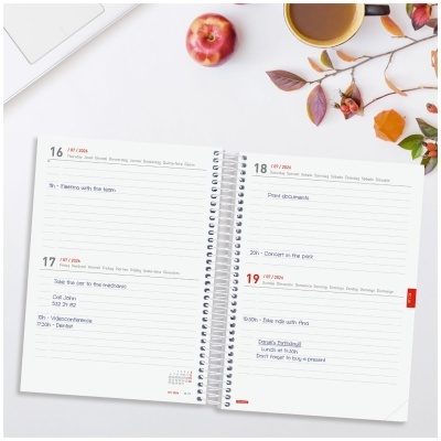 Agenda semanal aberta com texto manuscrito, caneca, maçã e folhas coloridas