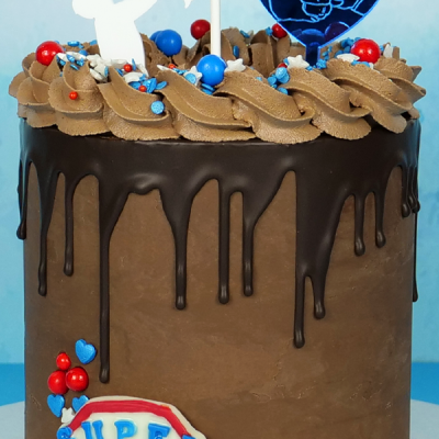 Bolo de chocolate com cobertura de chocolate e decoração colorida sobre fundo azul