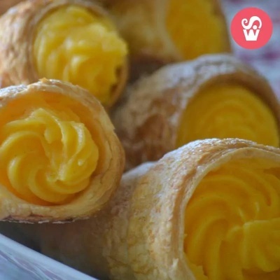 Caracoletas de massa folhada com recheio amarelo cremoso em fundo desfocado