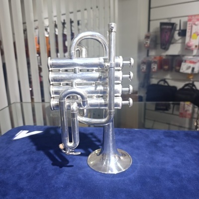 Trompete prateado sobre tecido azul numa loja de acessórios de instrumentos