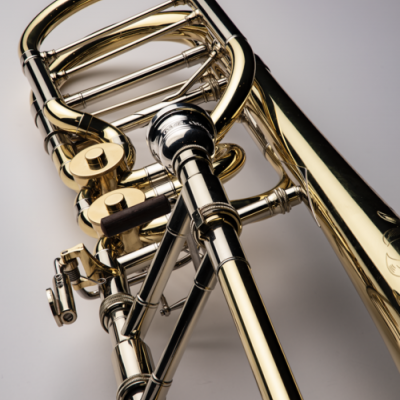 Trombone de metal dourado e prateado em close-up sobre fundo cinza claro
