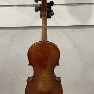 Violino castanho-avermelhado visto de trás pendurado numa parede branca