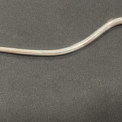 cano metálico com curvatura em gancho e rolha de cortiça, sobre tecido preto