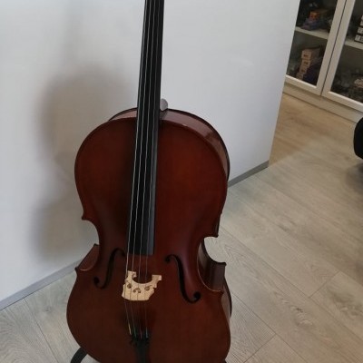 Violoncelo acústico em madeira castanha numa sala com chão de madeira clara