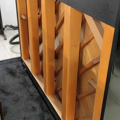 Móvel preto com estrutura de madeira clara e tapete preto