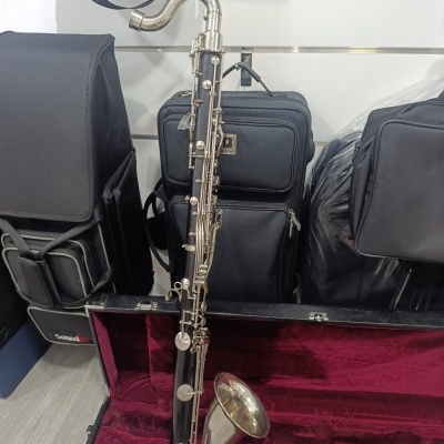 Saxofone tenor preto e prateado numa mala com interior vermelho e sacos para instrumentos pretos