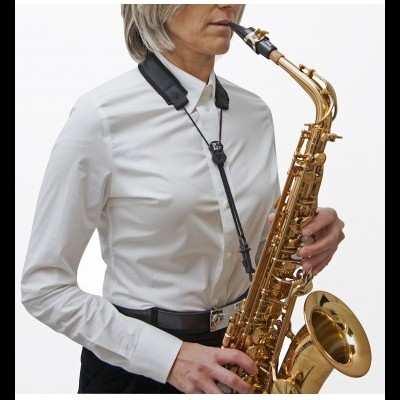 Pessoa tocando saxofone tenor dourado com correia preta
