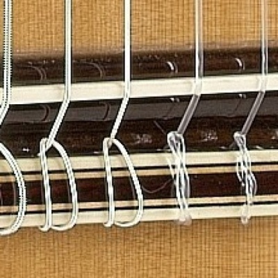 Close-up de cordas de nylon numa guitarra clássica sobre madeira clara e escura