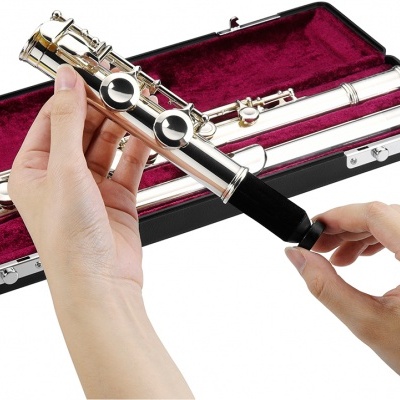 Flauta transversal prateada a ser montada em frente a um estojo preto forrado a vermelho