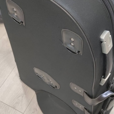 Mala preta rígida com fecho de correr e alças em chão de madeira