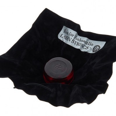 Frasco de vidro vermelho com tampa preta sobre tecido preto com etiqueta branca