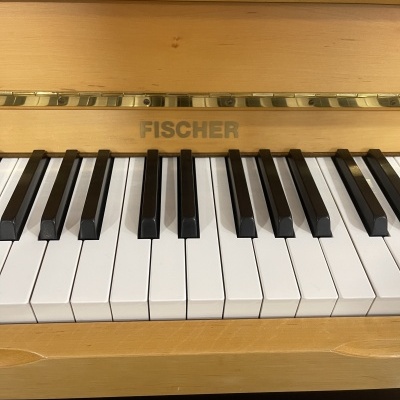 Teclado de piano acústico de madeira clara com teclas brancas e pretas