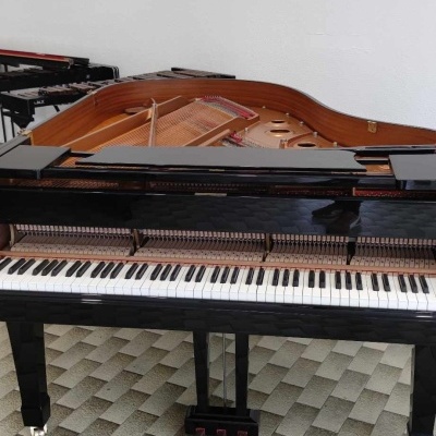 Piano de cauda preto aberto mostrando teclas e cordas, em piso geométrico cinza.