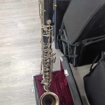 Saxofone em estojo vermelho com malas azuis e pretas no chão
