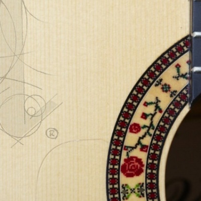 Guitarra clássica em madeira clara com padrão floral ao redor do buraco de som