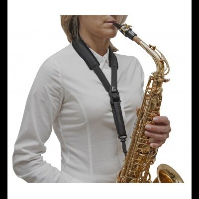 Pessoa tocando saxofone dourado com correia preta e camisa branca