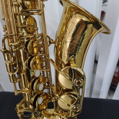 Saxofone tenor dourado com teclas e decoração gravada