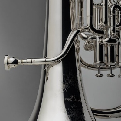 Instrumento musical de metal prateado com tubos e válvulas e gravuras florais