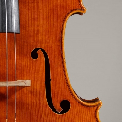 Parte de violino em madeira laranja com cordas e abertura em forma de 'f'