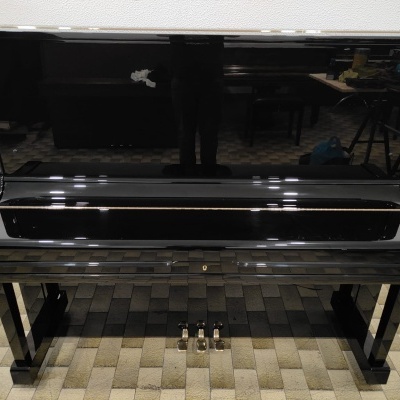 Piano de cauda preto com acabamento lacado brilhante e três pedais metálicos