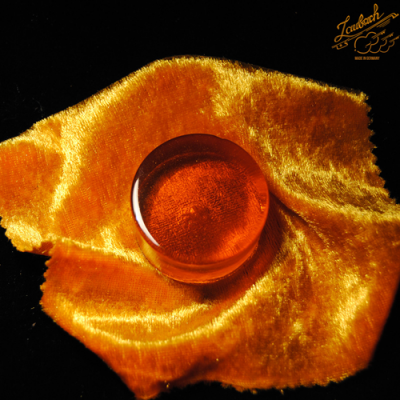 Pedra de âmbar sobre tecido amarelo aveludado com selo 'Lautasch' em fundo preto