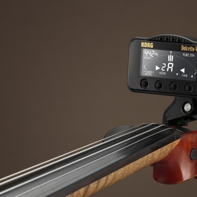 Afinador digital preto colocado na cabeça de um violino em madeira castanha