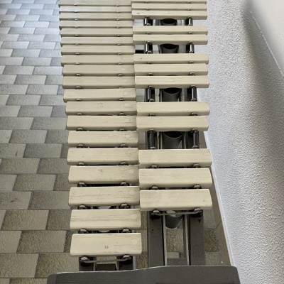 Banco de jardim com ripas brancas e estrutura preta junto a parede branca