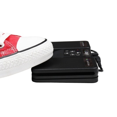 Sapato vermelho com sola branca sobre dispositivos electrónicos pretos empilhados