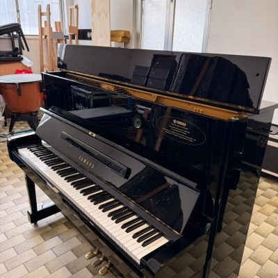 Piano vertical preto Yamaha com teclas e pedais