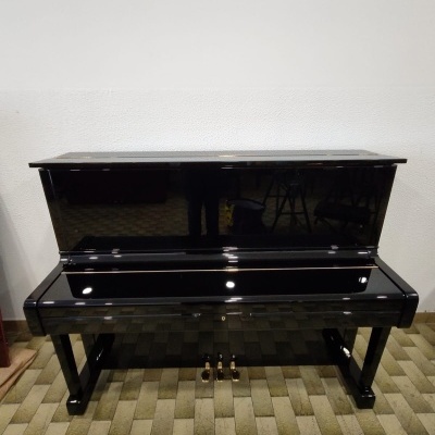 Piano preto de acabamento brilhante com 3 pedais em cima de chão de tijolos