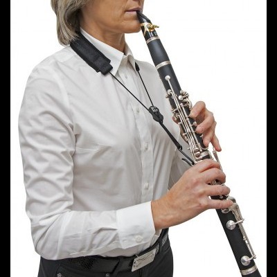 Pessoa vestida de branco a tocar clarinete preto com teclas prateadas