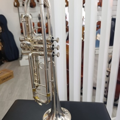 Trompete prateado numa loja de música com violinos ao fundo