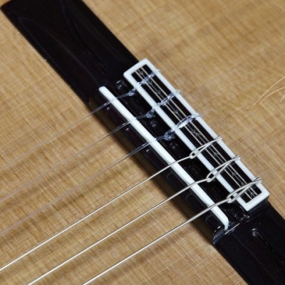Ponte e pestana de guitarra clássica em madeira clara com cordas brancas