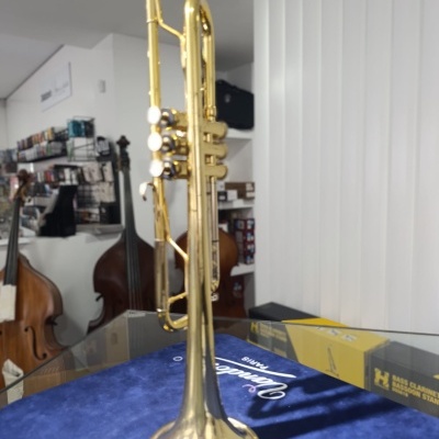Trompete dourado com pistões brancos sobre tecido azul em loja de instrumentos