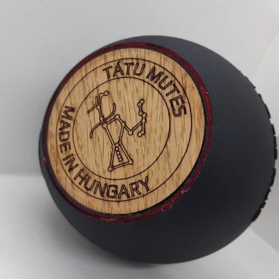 Esfera preta com tampa de madeira gravada com texto e figura, sobre superfície branca