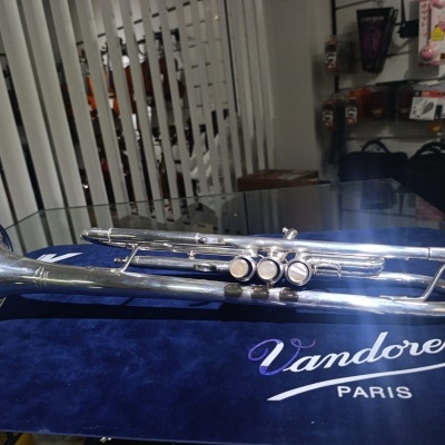 Trompete em metal prateado sobre pano azul Vandoren